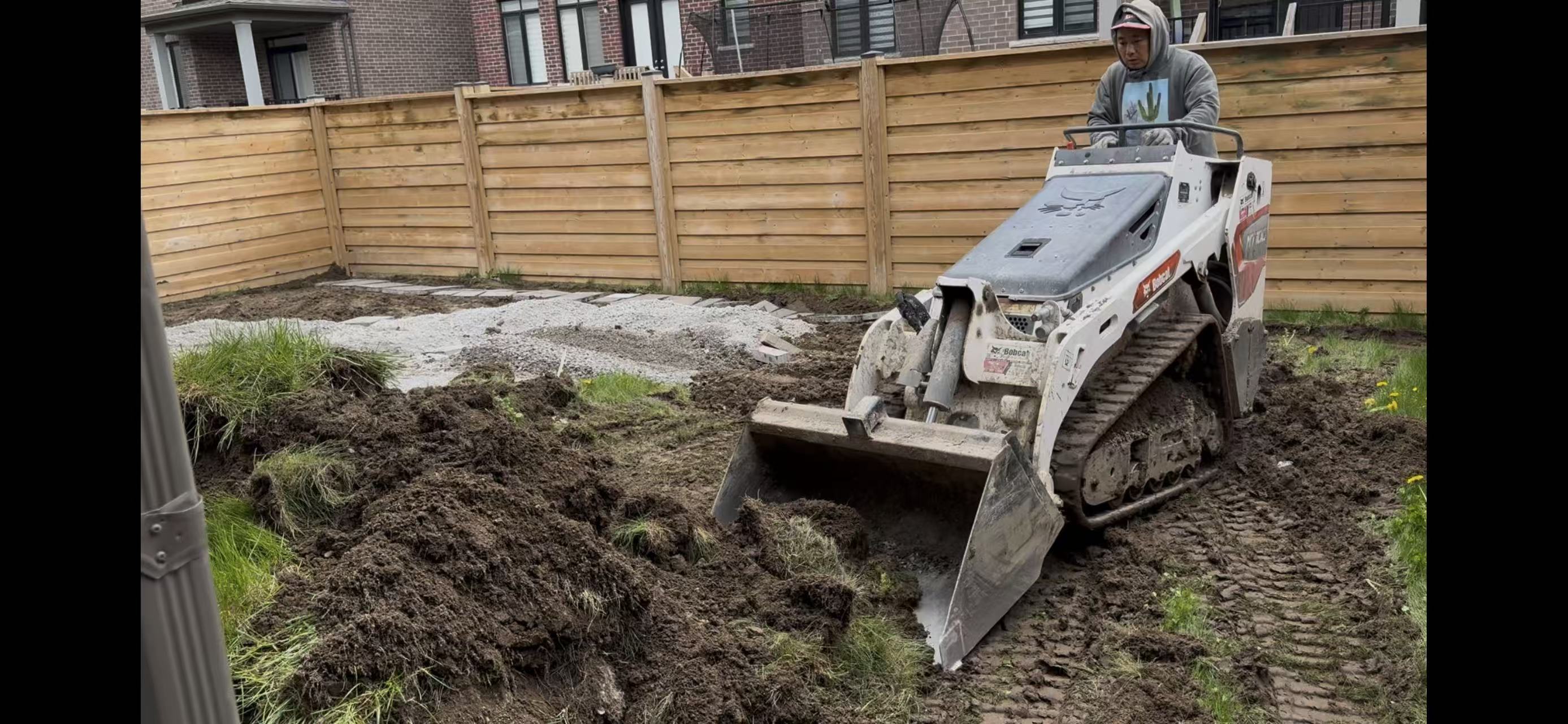 Skid-steer clearing sod and excavating the backyard to subgrade
